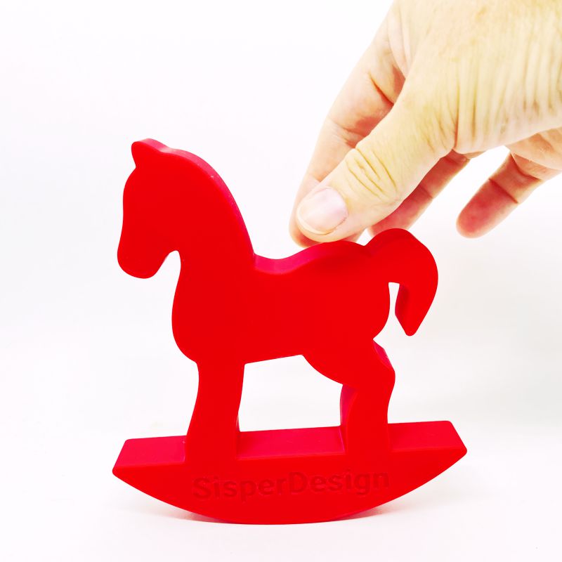 Cavalo Crioulo decorativo vermelho em formato de cavalinho de balanço da SisperDesign sobre fundo branco, sendo segurado por uma mão.